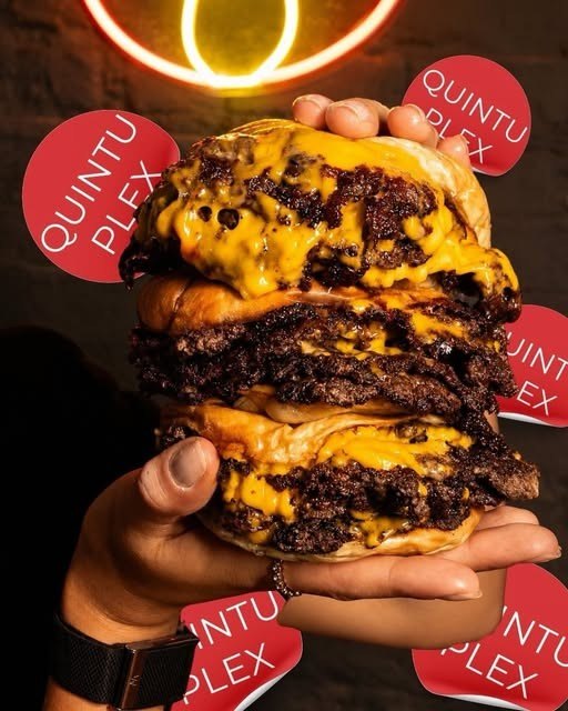 Quintuplex: cinco carnes con cheddar derretido, sostenida con la mano